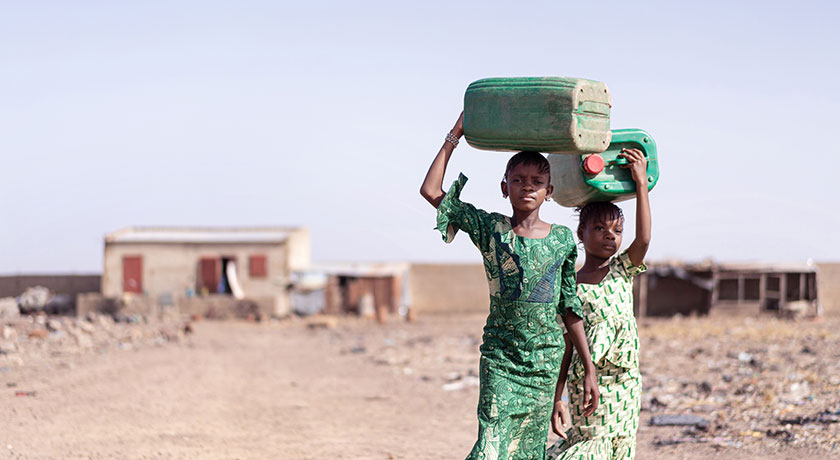 Two girls carrying water containers on their head Riccardo Niels Mayer Adobe Stock